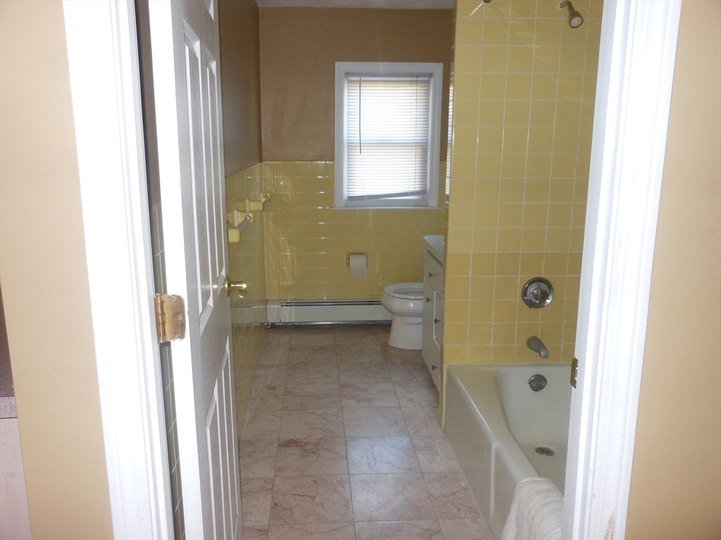21 Cook, Unit 1 Chelsea, MA 02150 - Photo 27 of 32 a bathroom with a granite countertop bathtub next to a toilet