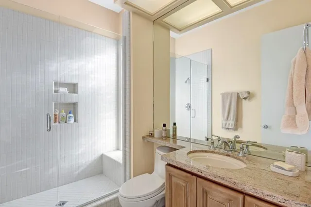 a bathroom with a granite countertop sink a toilet a mirror and shower