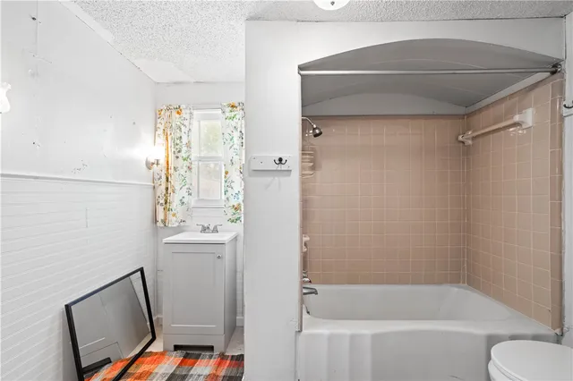 a bathroom with a bathtub shower sink vanity and toilet