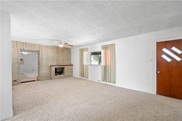 a view of an empty room with a fireplace and a window