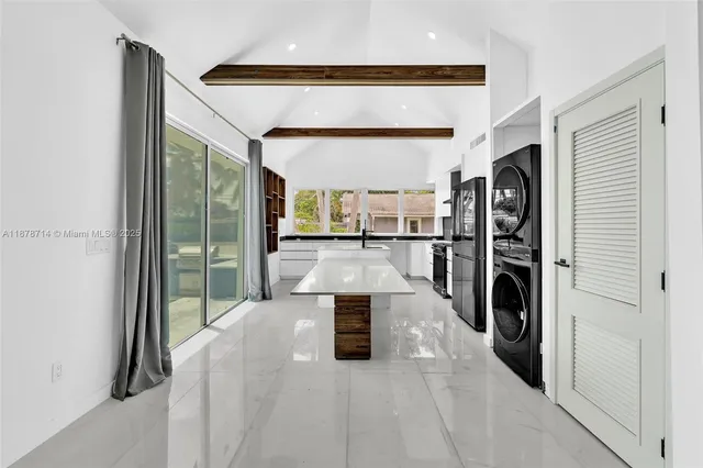 a large white kitchen with a large window and stainless steel appliances