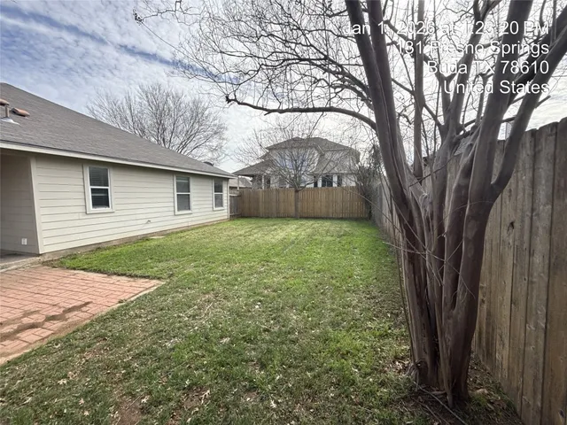 a backyard of a house with large trees and brick walls