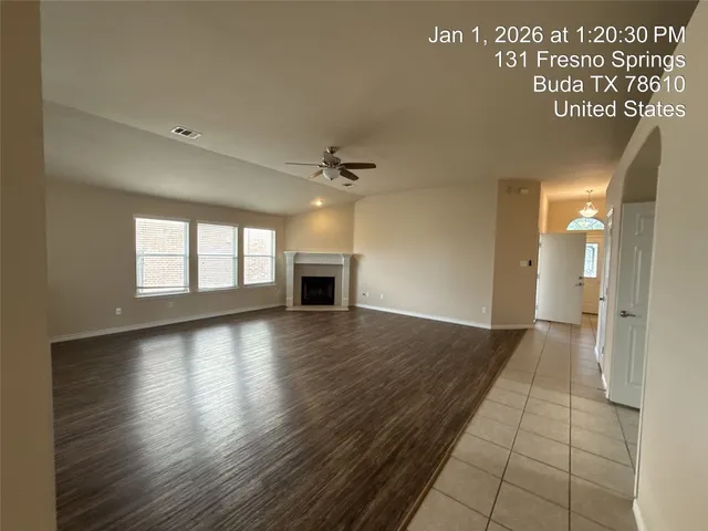 a view of an empty room with wooden floor and a ceiling fan