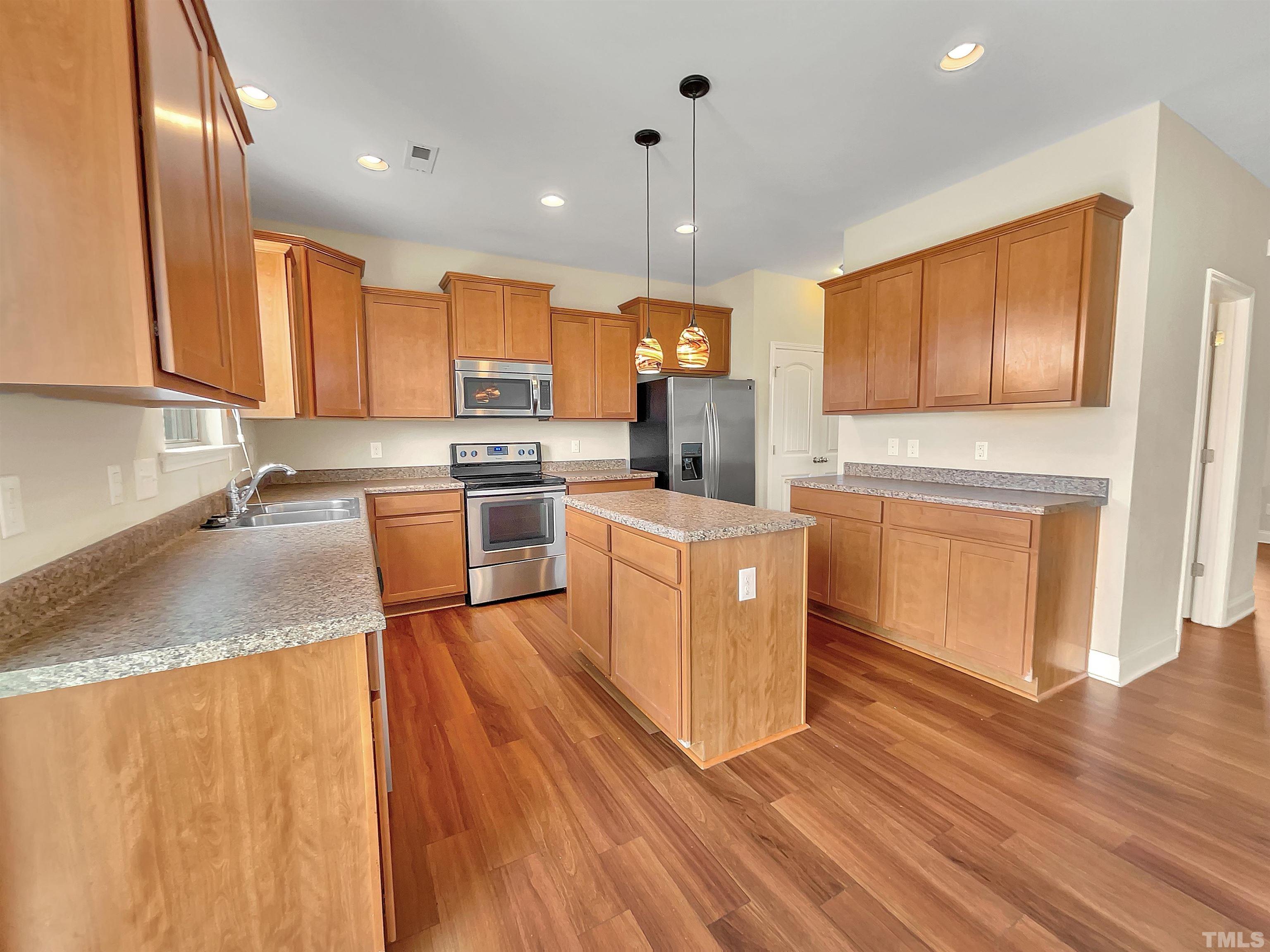 2709 Communion Court Raleigh, NC 27610 - Photo 2 of 18 a kitchen with stainless steel appliances granite countertop a stove a sink dishwasher and a refrigerator with wooden floor