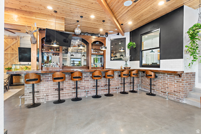 912 North Loafer Canyon Road Elk Ridge, UT 84651 - Photo 20 of 98 Vaulted wood-finish ceiling, brick-clad bar with wood-finish countertop, built-in shelving, concrete flooring, and an integrated window
