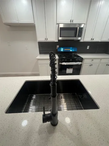 a kitchen with stainless steel appliances a white stove top oven cabinets and a wooden floor