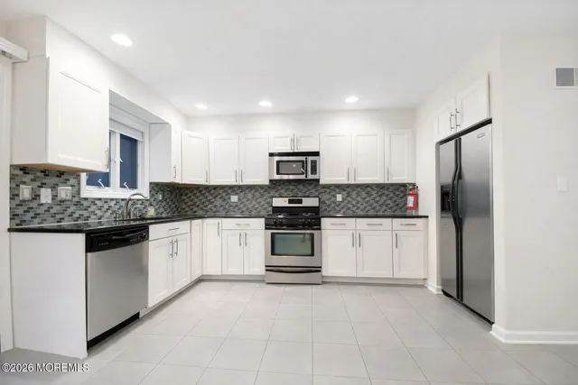 a kitchen with stainless steel appliances granite countertop a refrigerator and a stove top oven