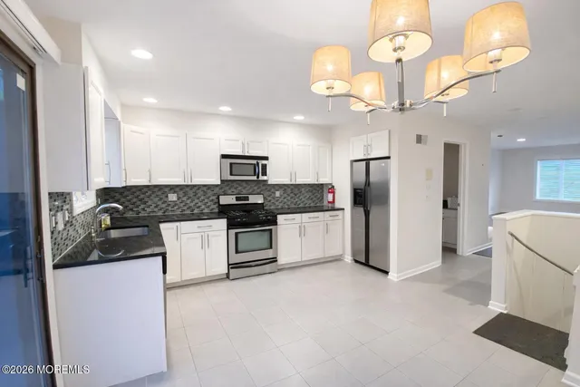 a large kitchen with a large counter top cabinets appliances and a ceiling fan