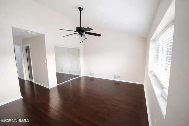 a view of an empty room with wooden floor and a window