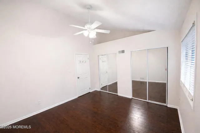 an empty room with wooden floor and fan