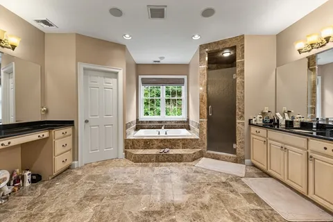 a spacious bathroom with a granite countertop sink a mirror and a bathtub