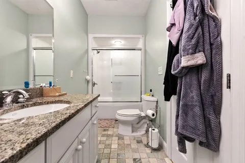a bathroom with a granite countertop sink toilet and shower