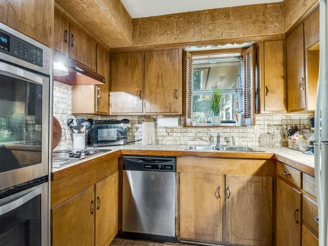 a kitchen with stainless steel appliances granite countertop a sink a stove and a refrigerator
