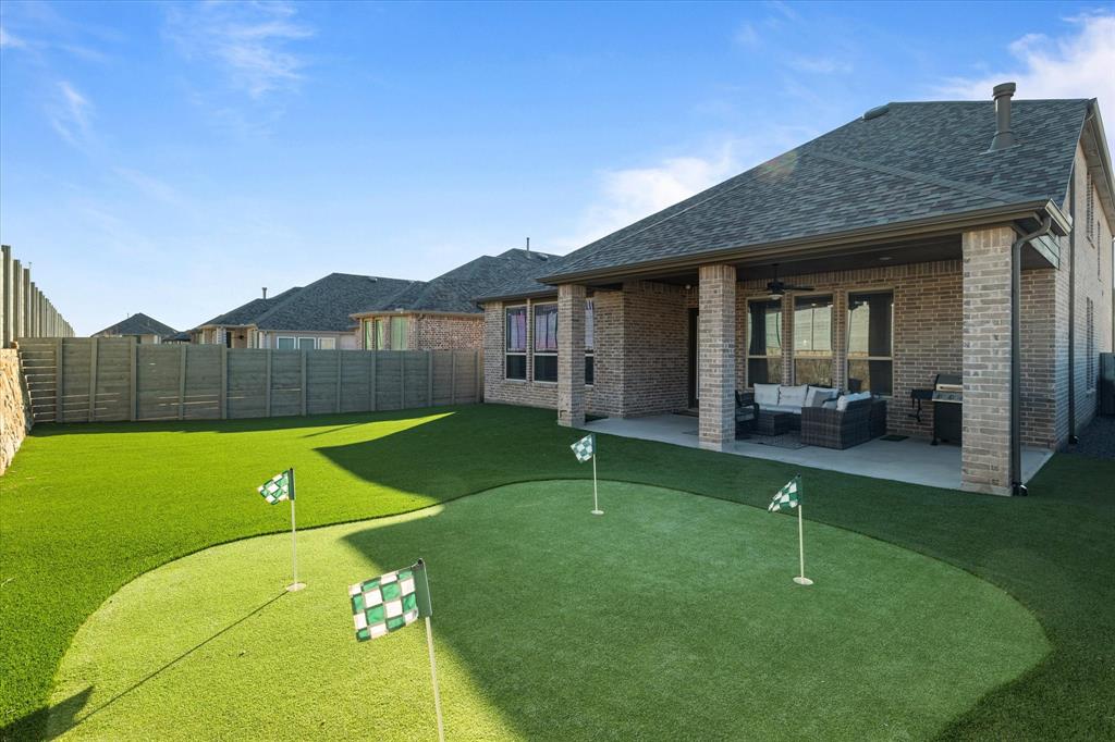 1332 Thompson Road Argyle, TX 76226 - Photo 2 of 36 Fenced backyard with ceiling fan, an outdoor lounge area, a patio, and a putting area
