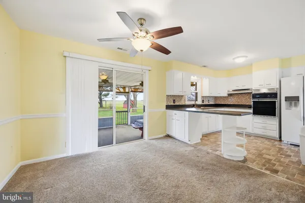 a kitchen with granite countertop a refrigerator a sink and white cabinets