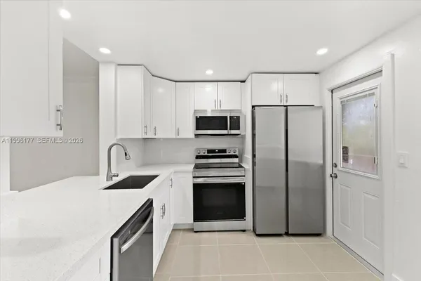 a kitchen with a refrigerator a stove top oven and white cabinets