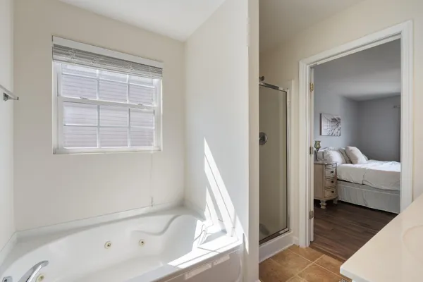 a bathroom with a tub shower and bedroom view