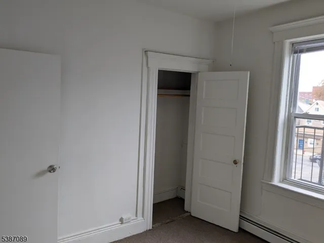 a view of empty room with windows and wardrobe