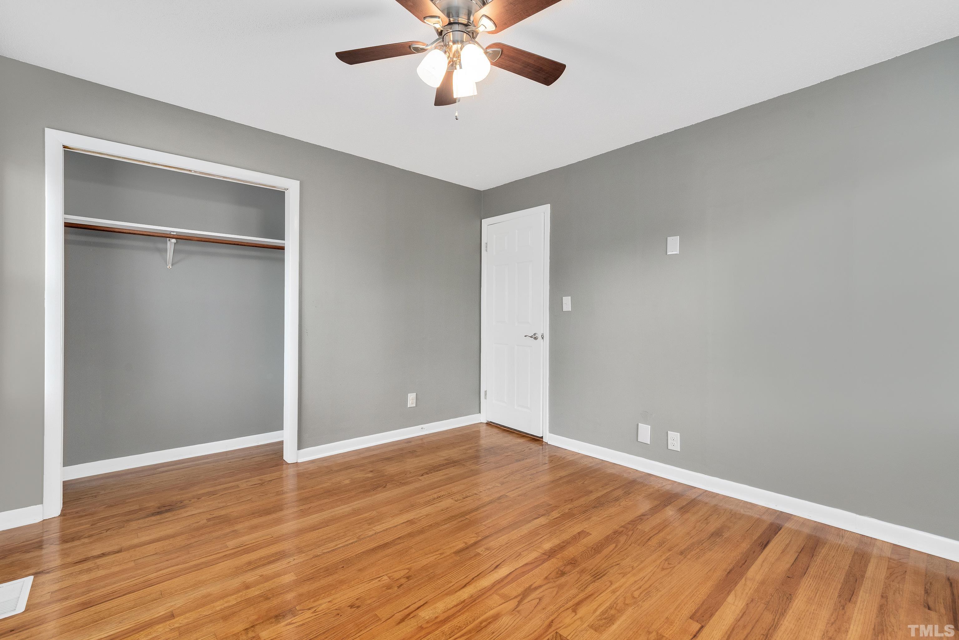 201 West B Street Erwin, NC 28339 - Photo 22 of 25 an empty room with wooden floor closet and fan