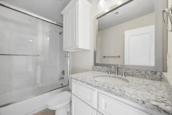 a bathroom with a granite countertop sink a toilet and shower