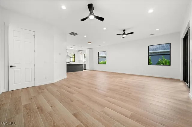 an empty room with ceiling fan and windows