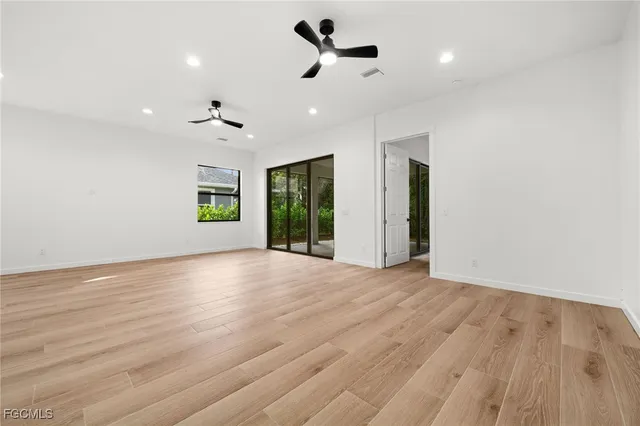 an empty room with ceiling fan and windows