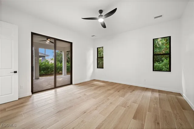 a view of empty room with wooden floor and fan
