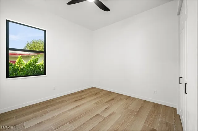 a view of an empty room with wooden floor and a window