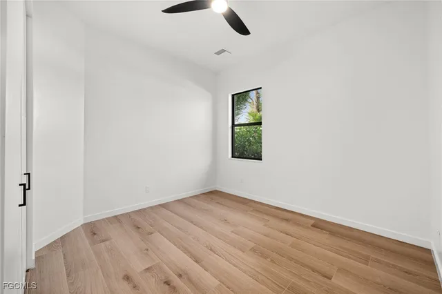 an empty room with a window and a ceiling fan