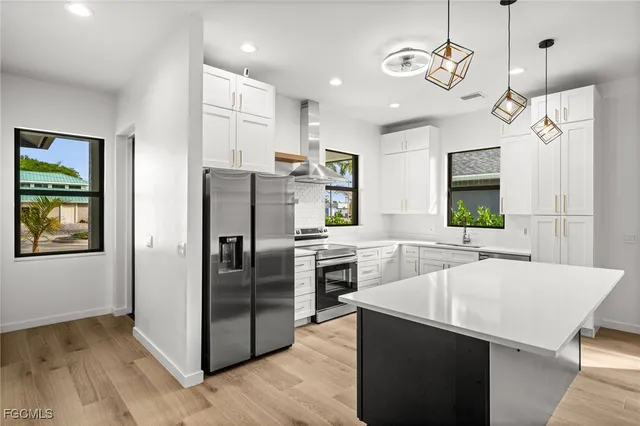 a kitchen with stainless steel appliances granite countertop a refrigerator a sink dishwasher a oven and a dining table with wooden floor