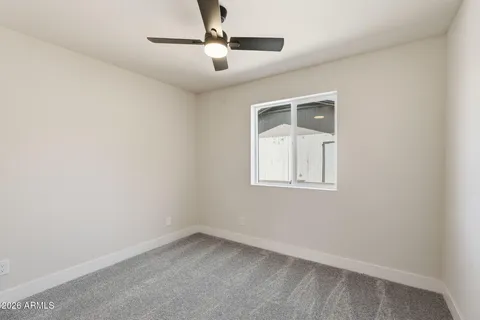 an empty room with a window and ceiling fan