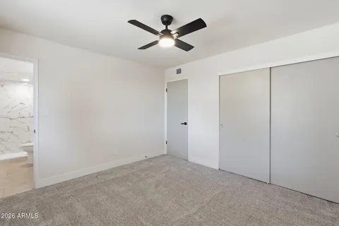 an empty room with closet and ceiling fan