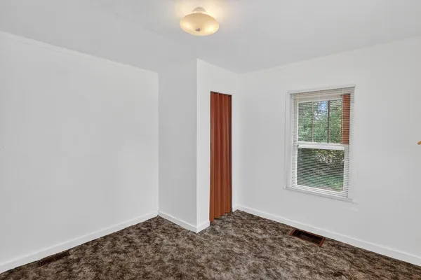 a view of an empty room with window and stairs