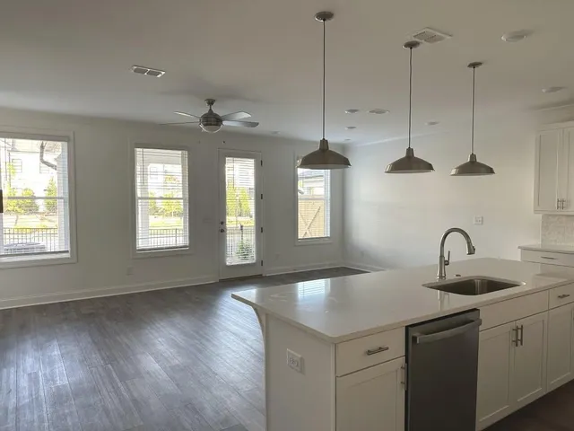 a kitchen with stainless steel appliances a sink a chandelier and wooden floor