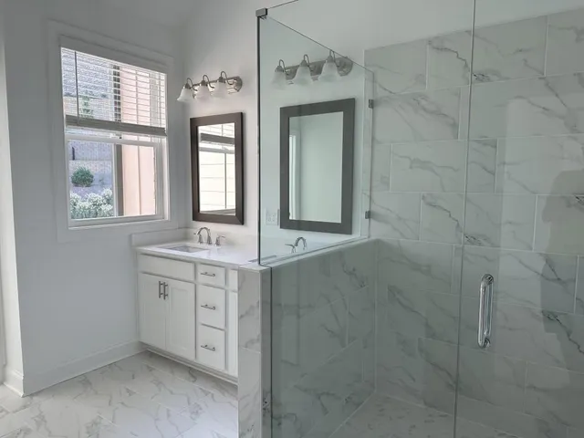 a bathroom with a granite countertop sink a mirror and a shower