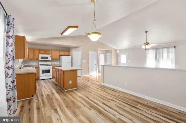 a open kitchen with a refrigerator a stove top oven a sink dishwasher and a dining table with wooden floor