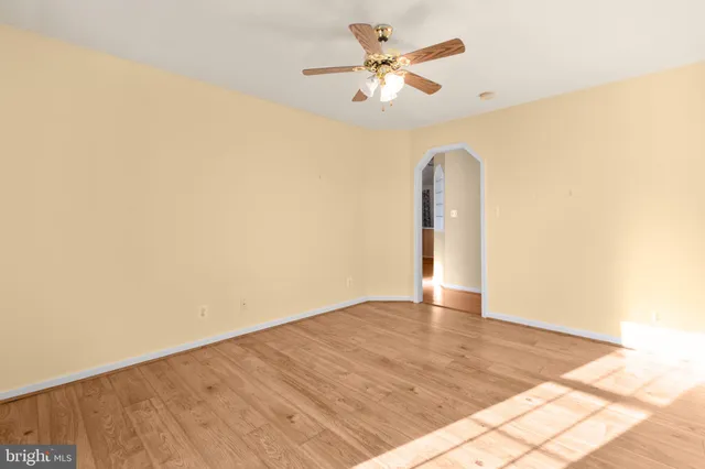 an empty room with wooden floor and a ceiling fan