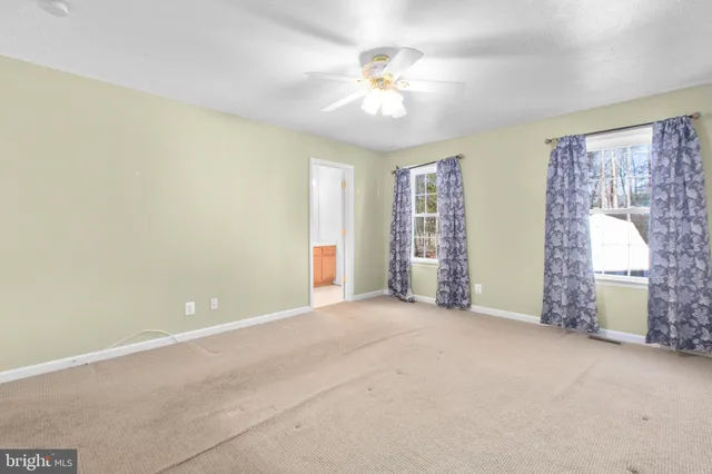 an empty room with windows and chandelier fan