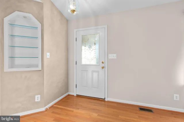 a view of an empty room with wooden floor and closet