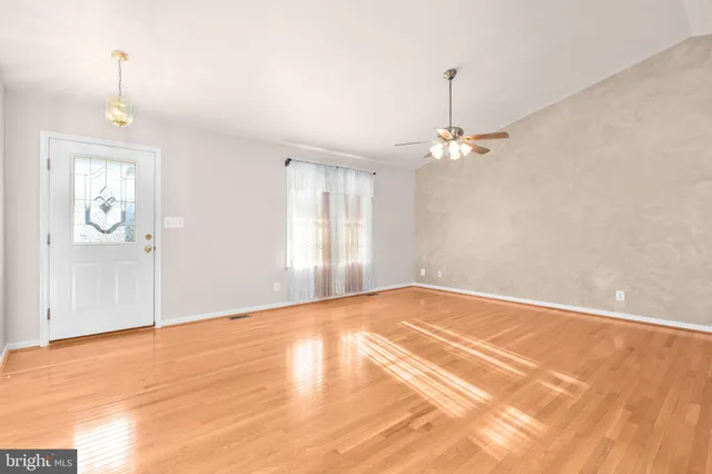 a view of an empty room with window and wooden floor