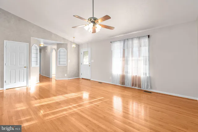 a view of an empty room with window and wooden floor
