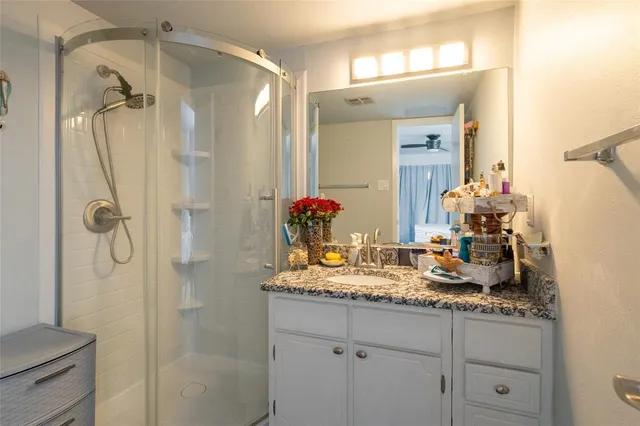 a bathroom with a granite countertop shower sink vanity and mirror