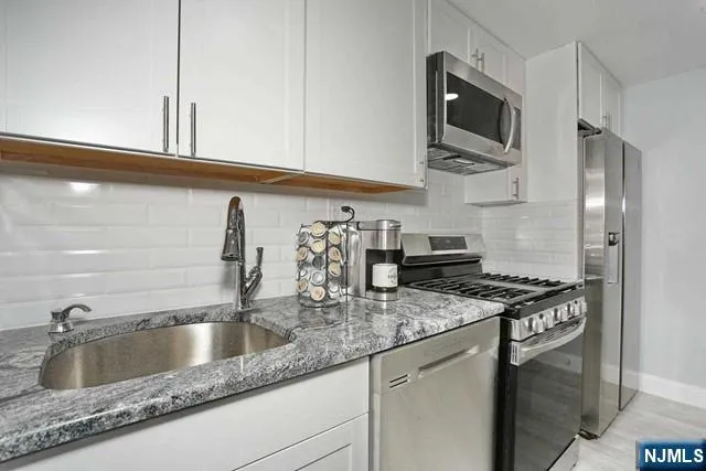a kitchen with granite countertop a sink stainless steel appliances and cabinets
