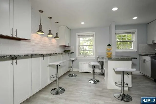 a kitchen with granite countertop a stove a sink a window and chairs