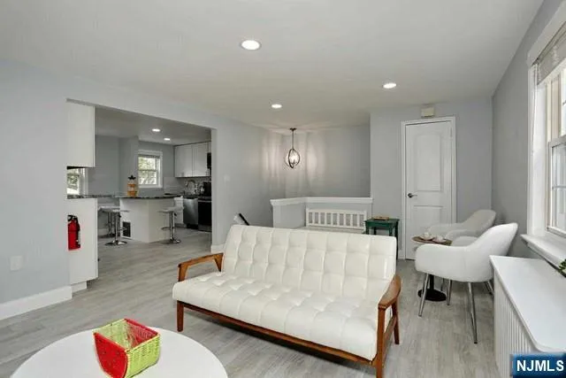 a living room with furniture and a dining table with wooden floor