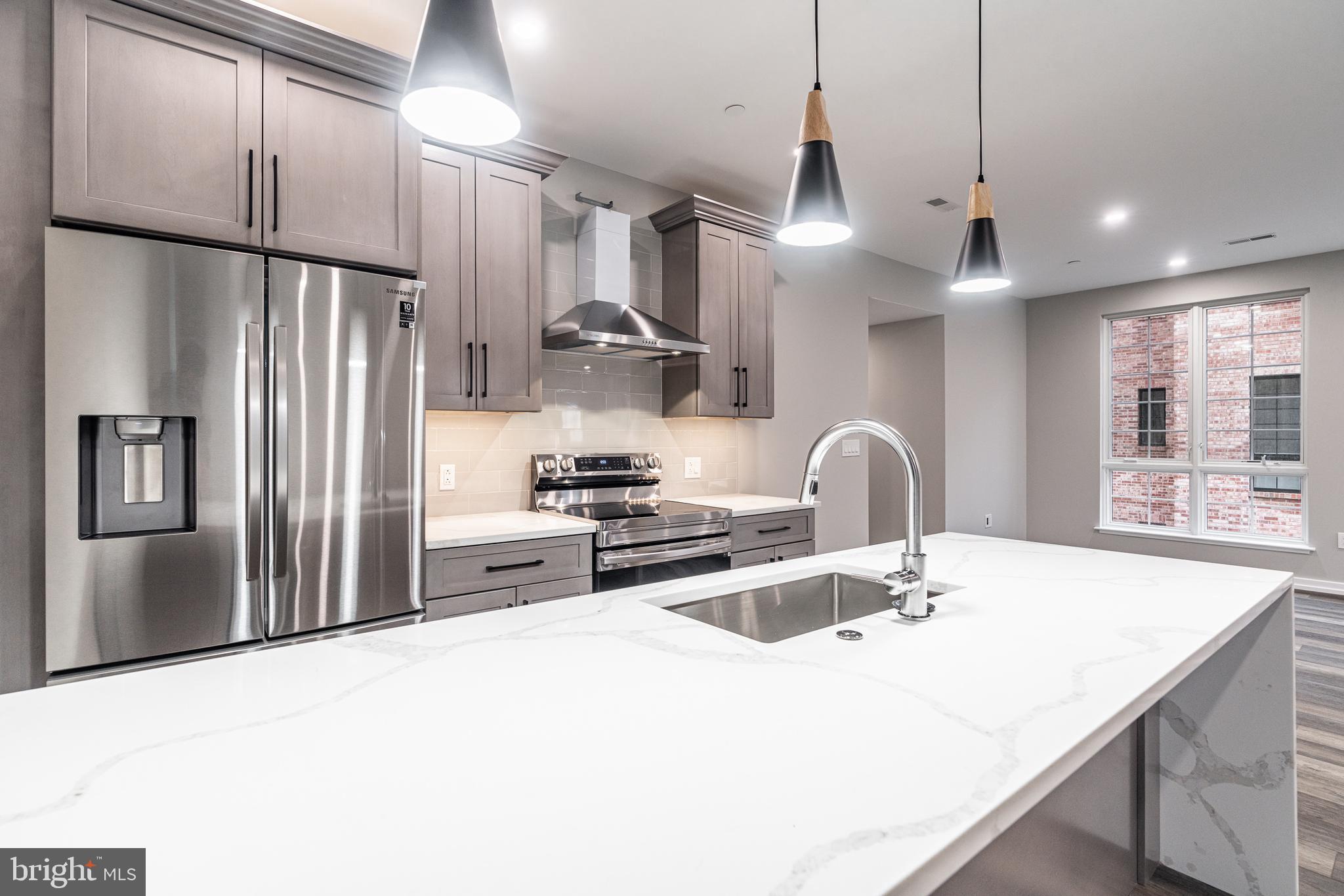 2412 Innovator Way, Unit 3 Philadelphia, PA 19146 - Photo 8 of 25 a kitchen with stainless steel appliances a sink a stove a refrigerator cabinets a dining table and chairs