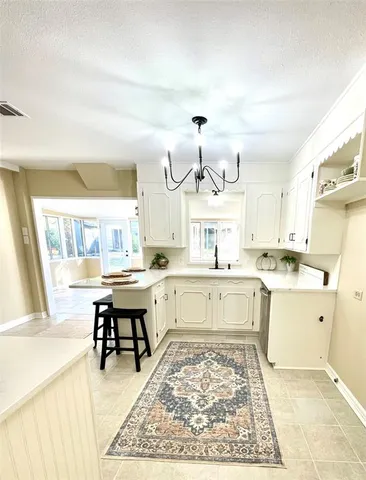 a large white kitchen with a white stove a sink dishwasher and a dining table with wooden floor