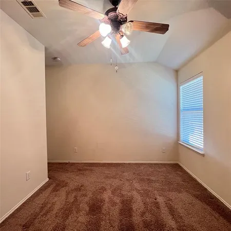 an empty room with a chandelier fan and windows