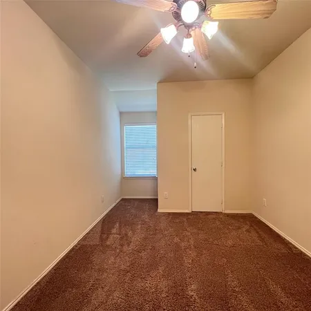 an empty room with a chandelier fan and closet area