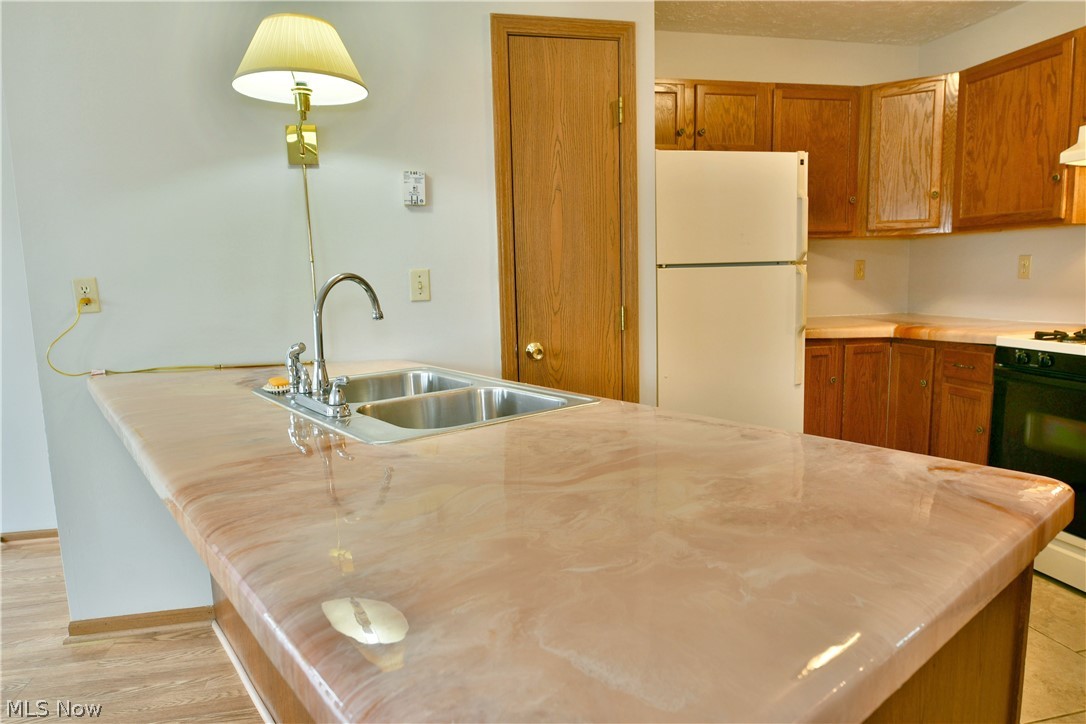 3287 Pheasant Run Road, Unit B Cortland, OH 44410 - Photo 22 of 45 Kitchen featuring wood-finish cabinetry, a double basin stainless steel sink, and a multi-tone countertop